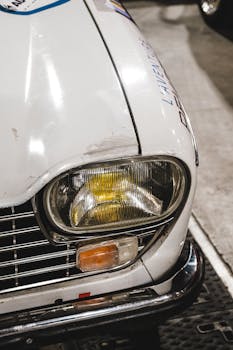 Close-up of a vintage car's headlight, showcasing its classic design in a garage setting.