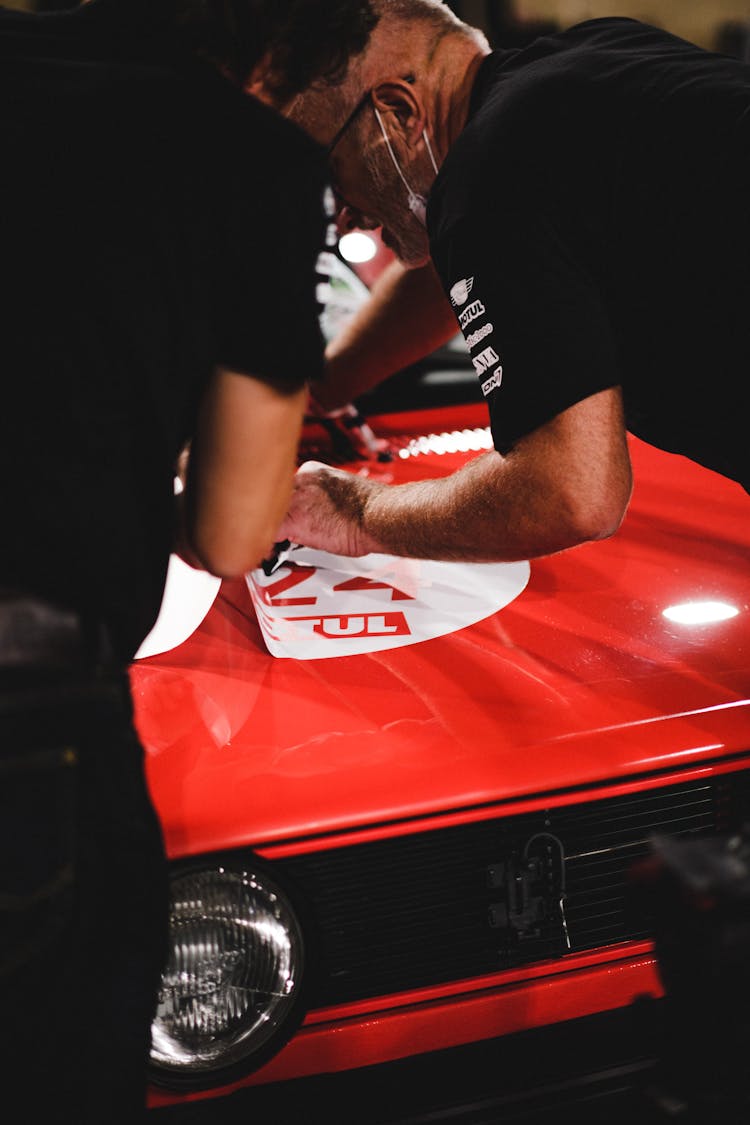 Men Putting Stickers On A Car