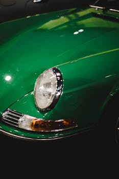 Close-up of a vintage green car highlighting the classic design and headlight details.