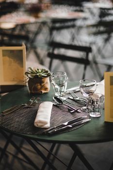 A beautifully arranged table with cutlery, glasses, and a plant centerpiece in a cozy restaurant setting.