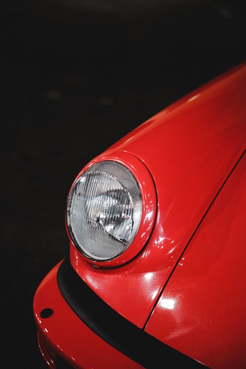 Free Detailed look at the headlight of a classic red car, showcasing vintage automobile design. Stock Photo