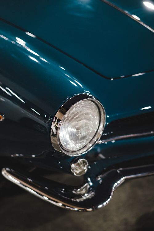 Free Detailed close-up of a classic vintage car's headlight and front bumper, showcasing its elegant design. Stock Photo