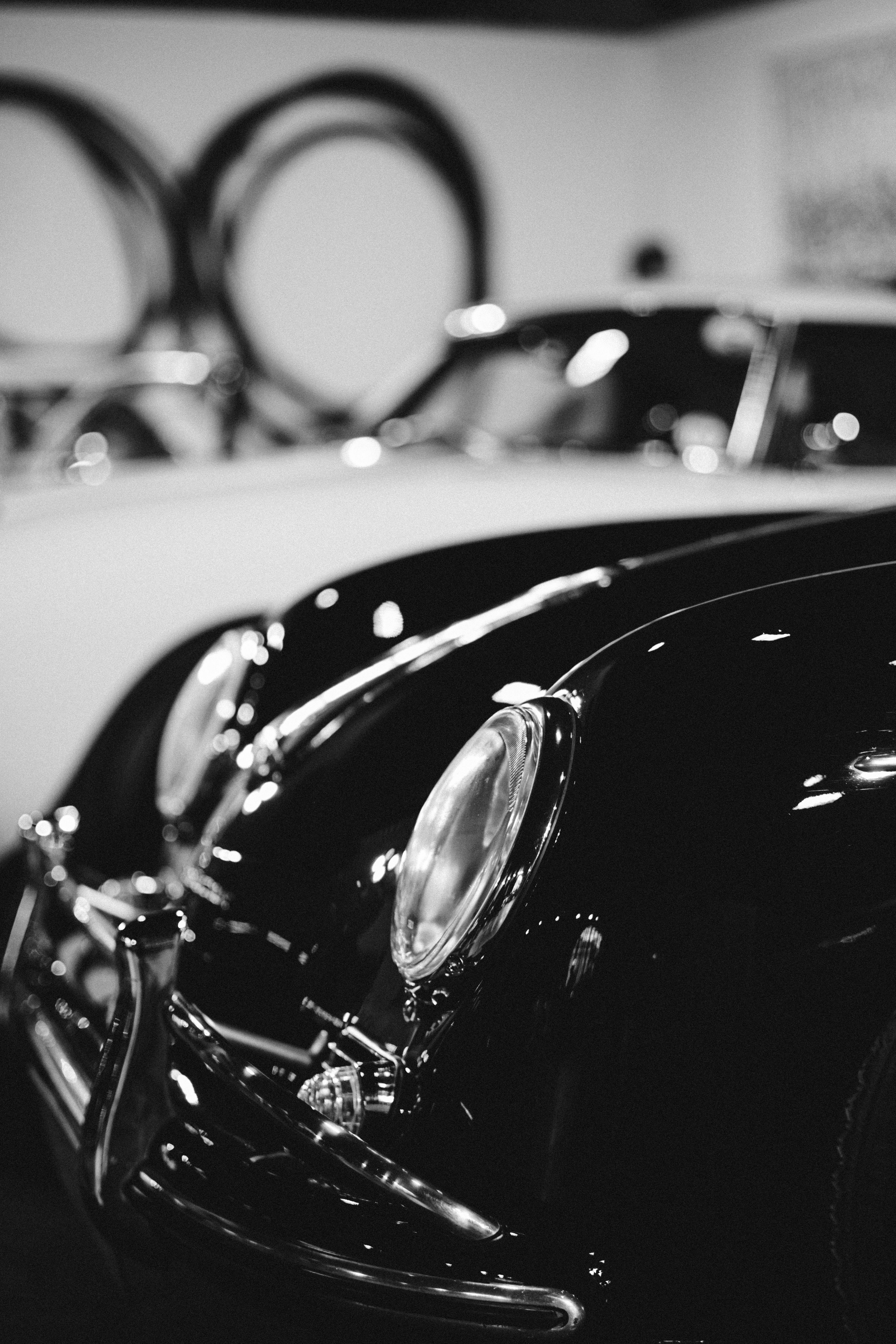 Elegant black and white close-up of a vintage car headlamp highlighting its shiny chrome features.