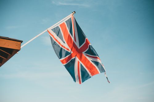 Free Union Jack flap in the breeze against a clear blue sky, symbolizing British pride. Stock Photo