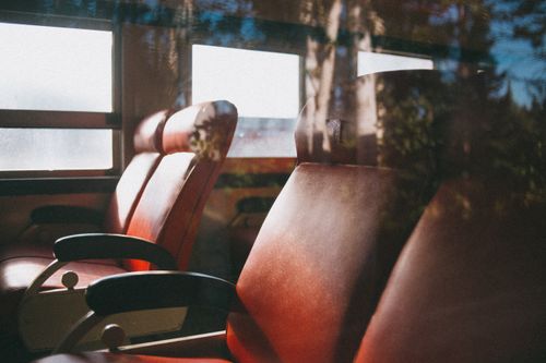 Free Sunlight streaming through train windows illuminating empty red seats, creating a warm atmosphere. Stock Photo