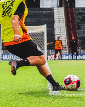 A soccer player kicks a ball during training on a grass field.