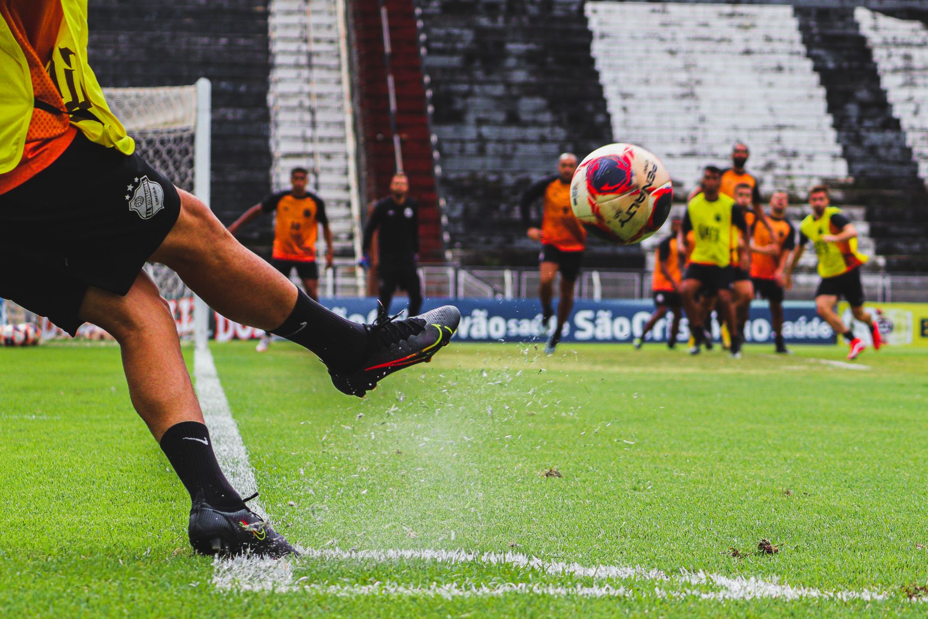 Nike Mercurial Vapor 16 Pro resting on a white sideline, with sprint drills visible behind