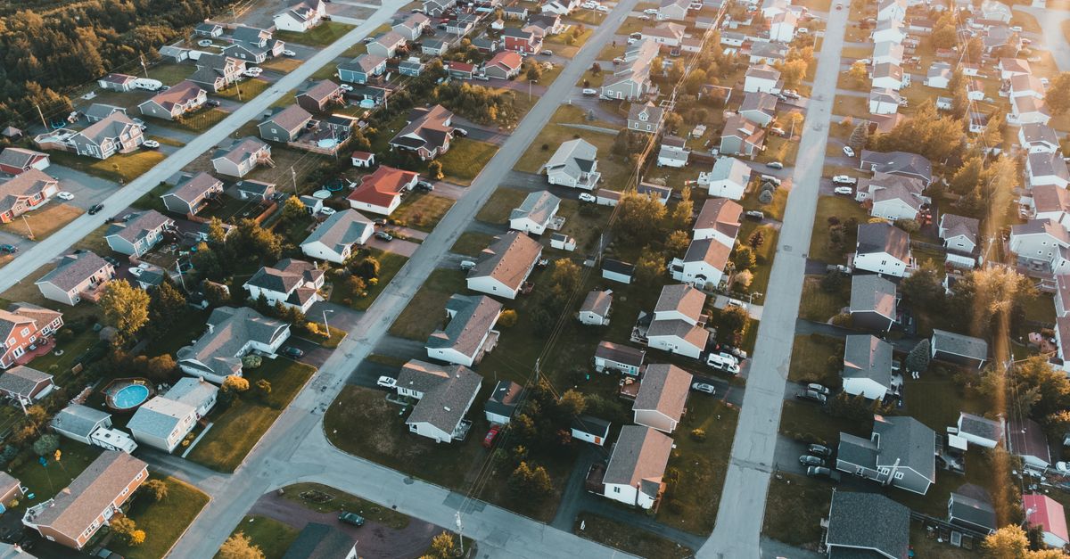 A stunning aerial view of a peaceful suburban neighborhood at sunset with lined houses and streets.