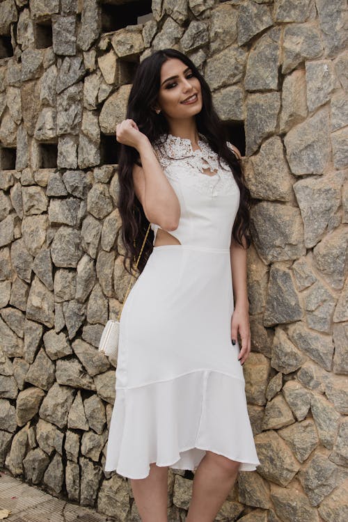 Free 사진을 위해 포즈를 취하는 벽돌 벽에 기대어 흰 드레스 여자 Stock Photo