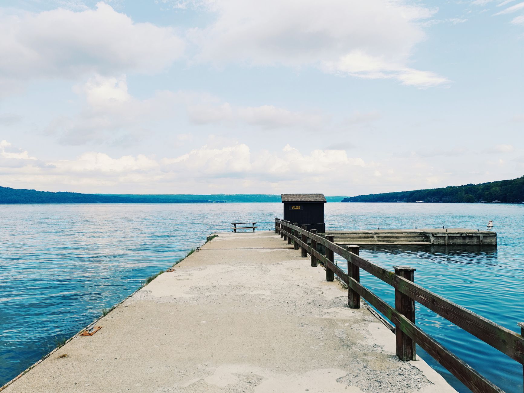 Wooden pier reaching out over calm Canandaigua Lake in the Finger Lakes