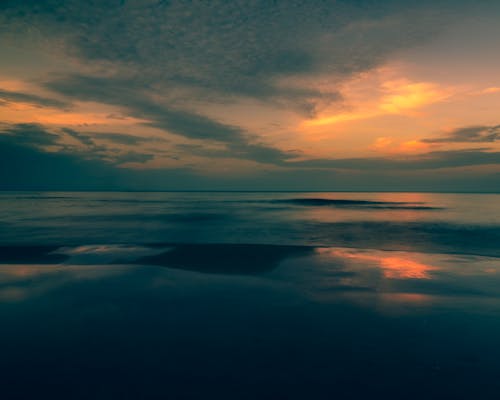 Body of Water Under Dark Clouds during Sunset