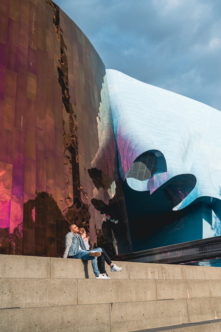 Man And Woman Sitting On Steps In City