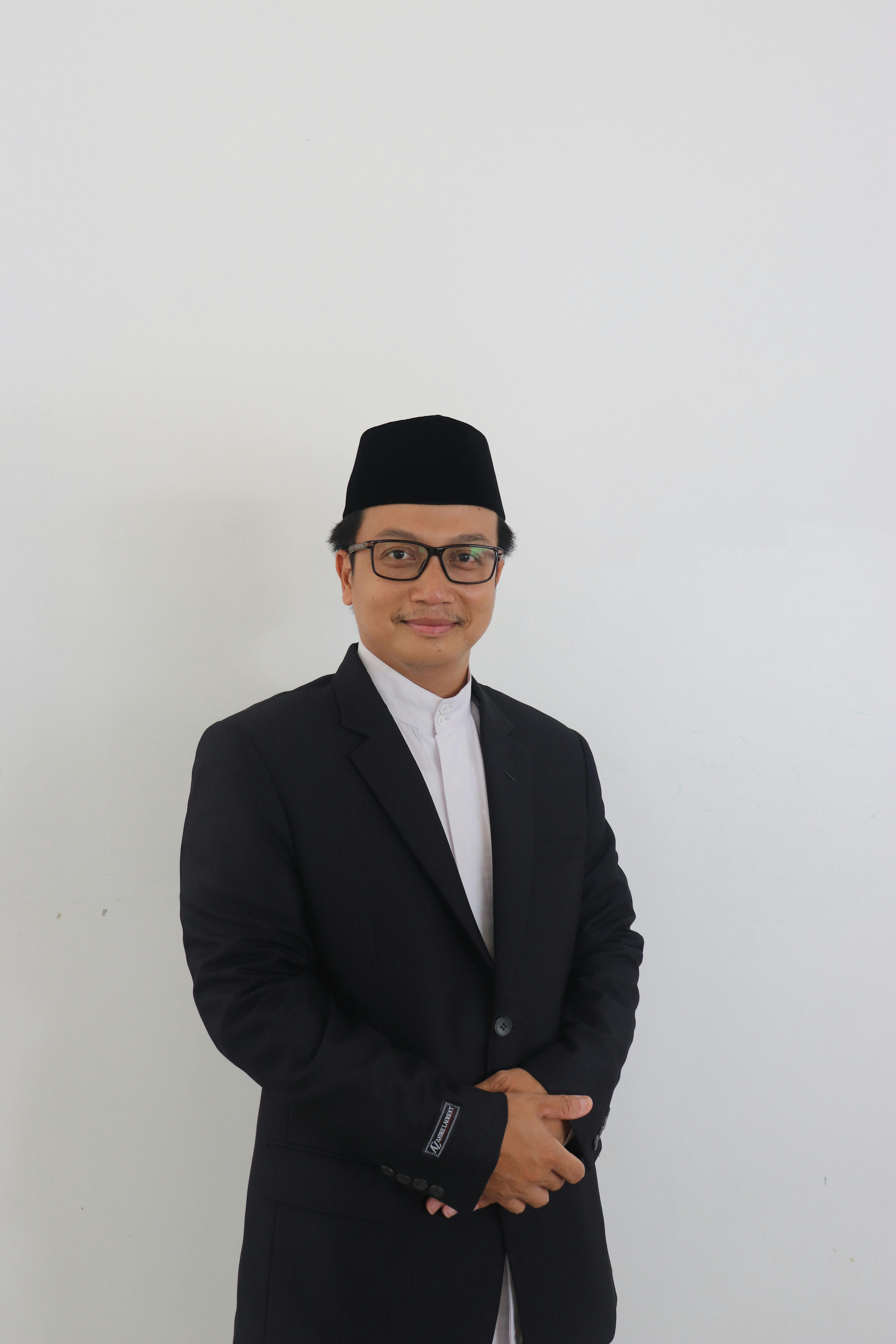 Portrait of a confident man in a suit and hat, posing against a white background.