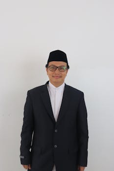 Portrait of a smiling man wearing a suit and kufi hat against a white background.