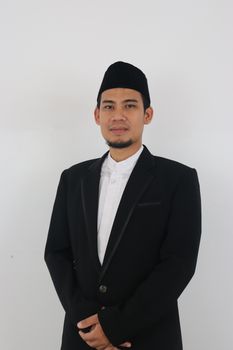 Portrait of a confident man wearing a suit and taqiyah against a clean white background. - Fotografer Sidoarjo