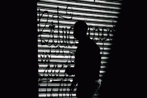 Silhouette of Person Standing Near a Wall