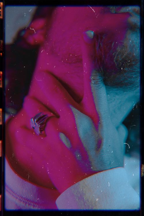 Free A vibrant artistic shot featuring a ringed hand touching a man's beard with colorful lighting. Stock Photo