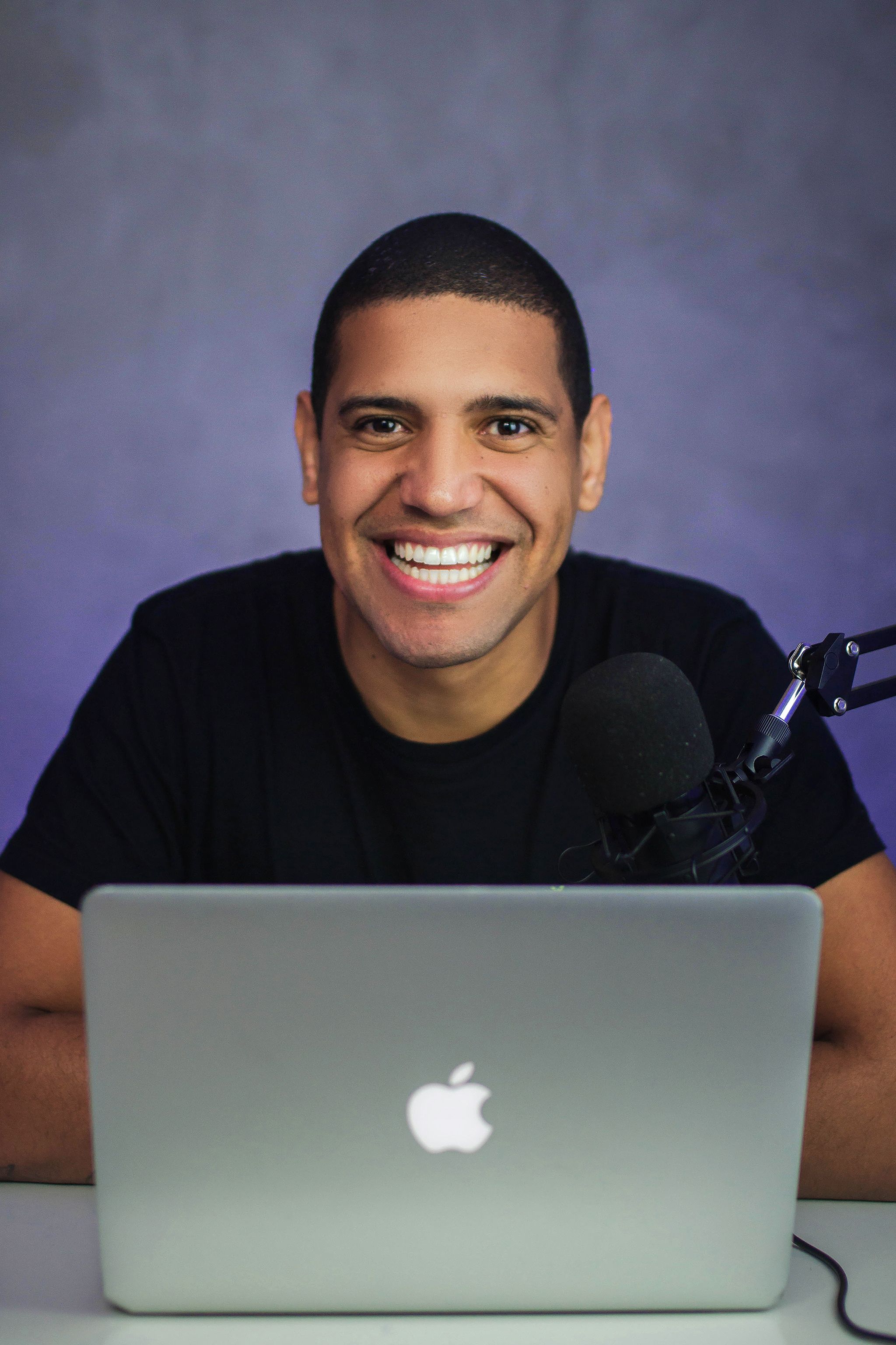 Cheerful man using a laptop with microphone setup, perfect for tech blogs.