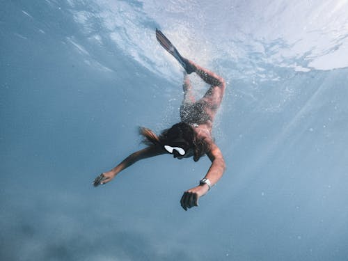Woman in Black and White Bikini Swimming in Blue Water