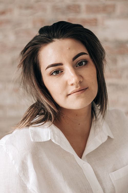 Free Close-up portrait of a young woman with short hair and a serene expression, set against a textured background. Stock Photo