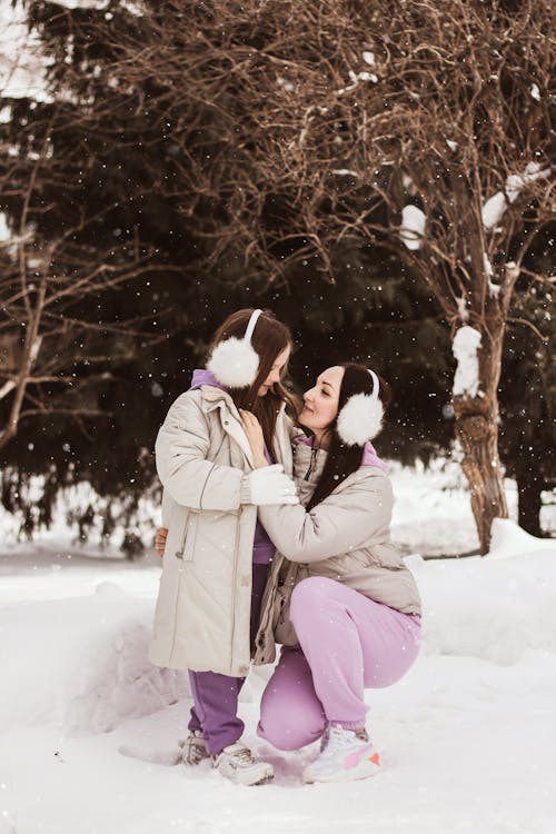 Free Woman in Gray Coat Kissing Woman in Gray Coat on Snow Covered Ground Stock Photo
