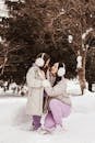 Woman in Gray Coat Kissing Woman in Gray Coat on Snow Covered Ground