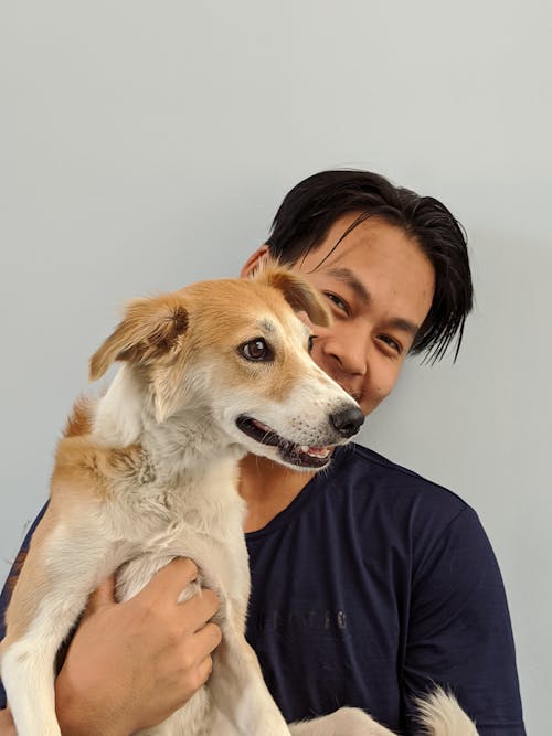 Man in Blue Shirt Holding a Dog