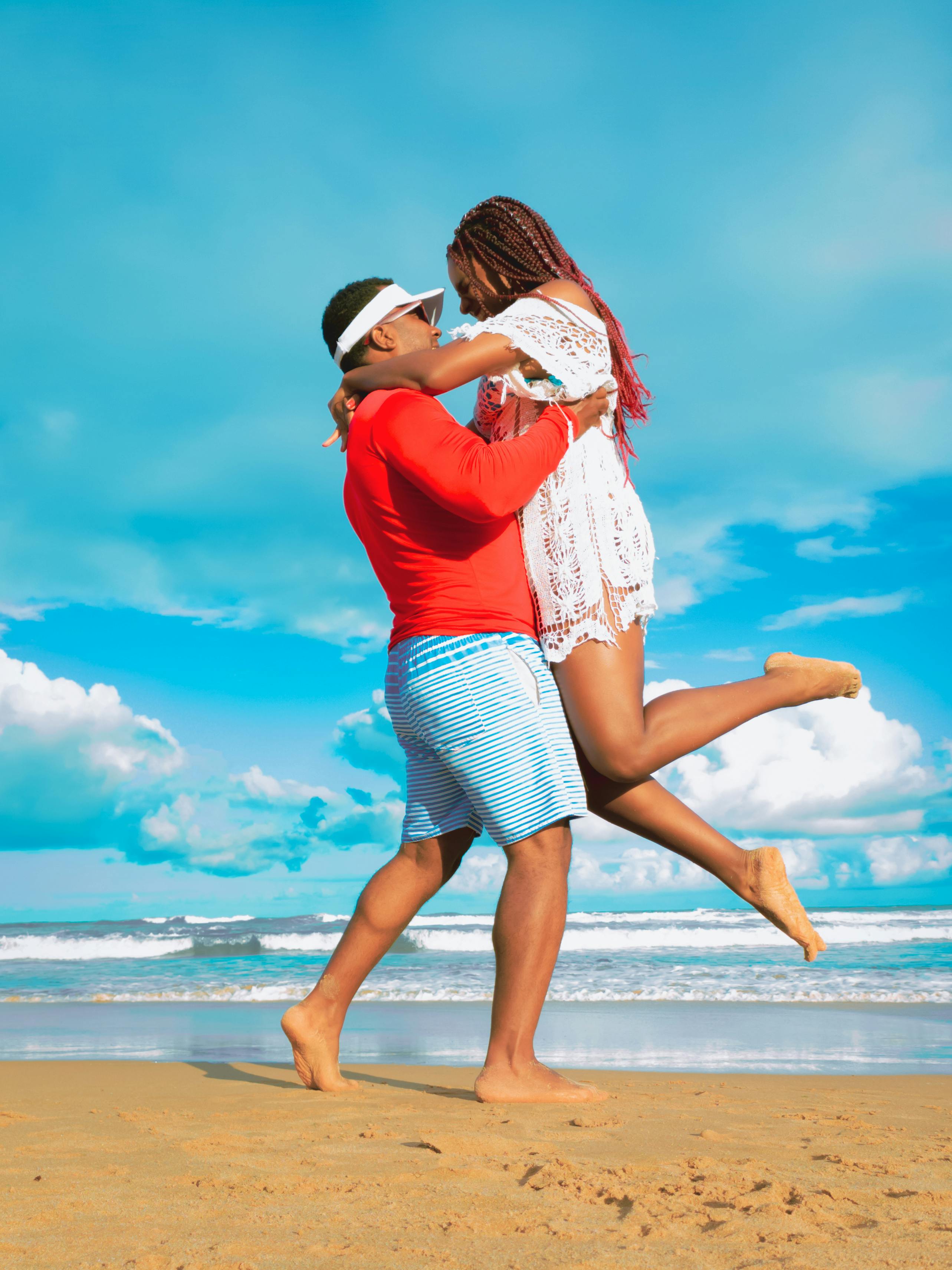 A joyful couple shares a loving embrace on a sunny beach day in Brazil.