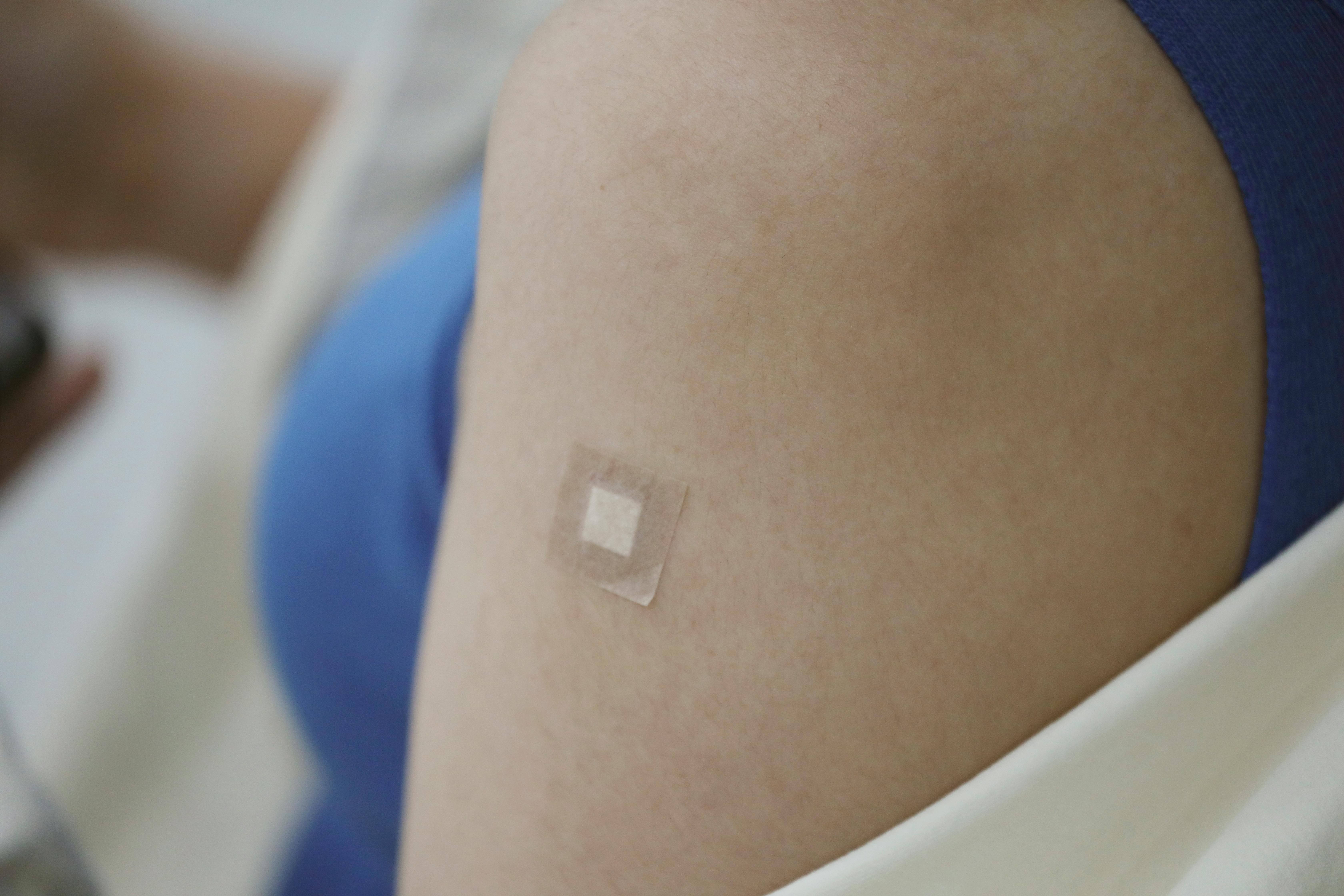 A close-up image showing a Band-Aid on an arm following a medical vaccination.