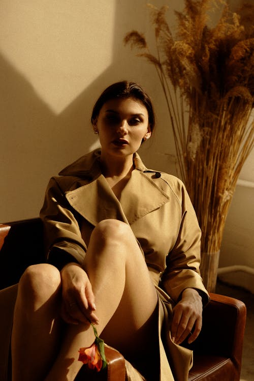 Woman in Brown Trench Coat Sitting on Sofa Chair