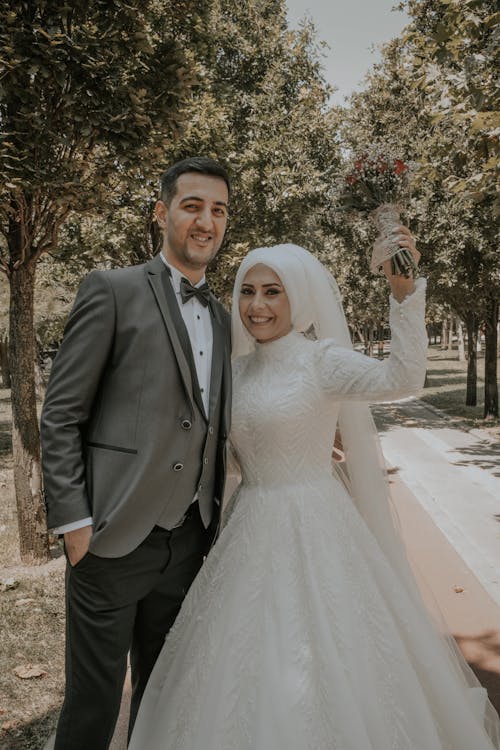 Bride Holding Bouquet of Flowers While Standing Beside a Man