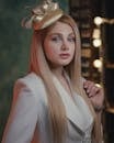 A Beautiful Woman in Beige Blazer and Fascinator Hat Looking at the Camera