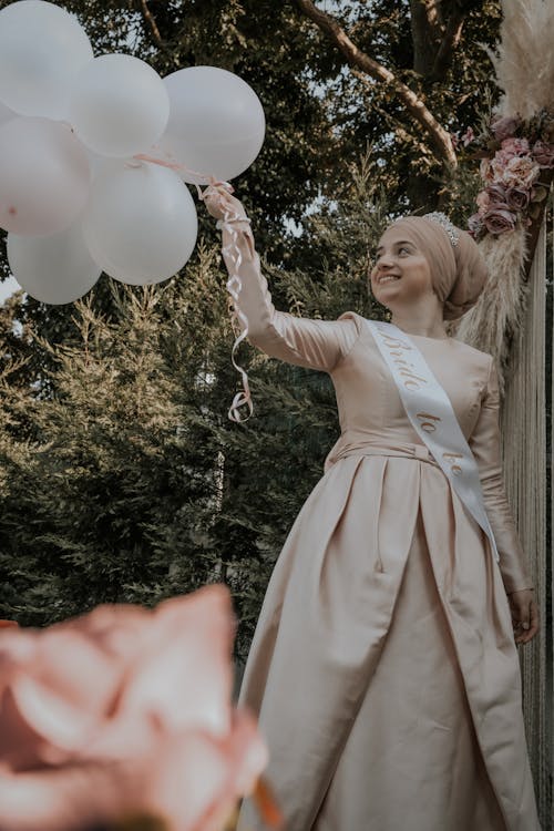 Free A Woman in Dress Holding White Balloons Stock Photo
