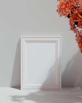 Minimalist white wooden frame next to vibrant autumn maple leaves casting shadows.