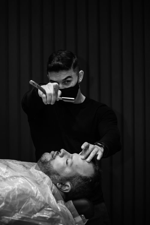 Free A skillful barber shaving a client's beard in a classic barbershop setting. Stock Photo