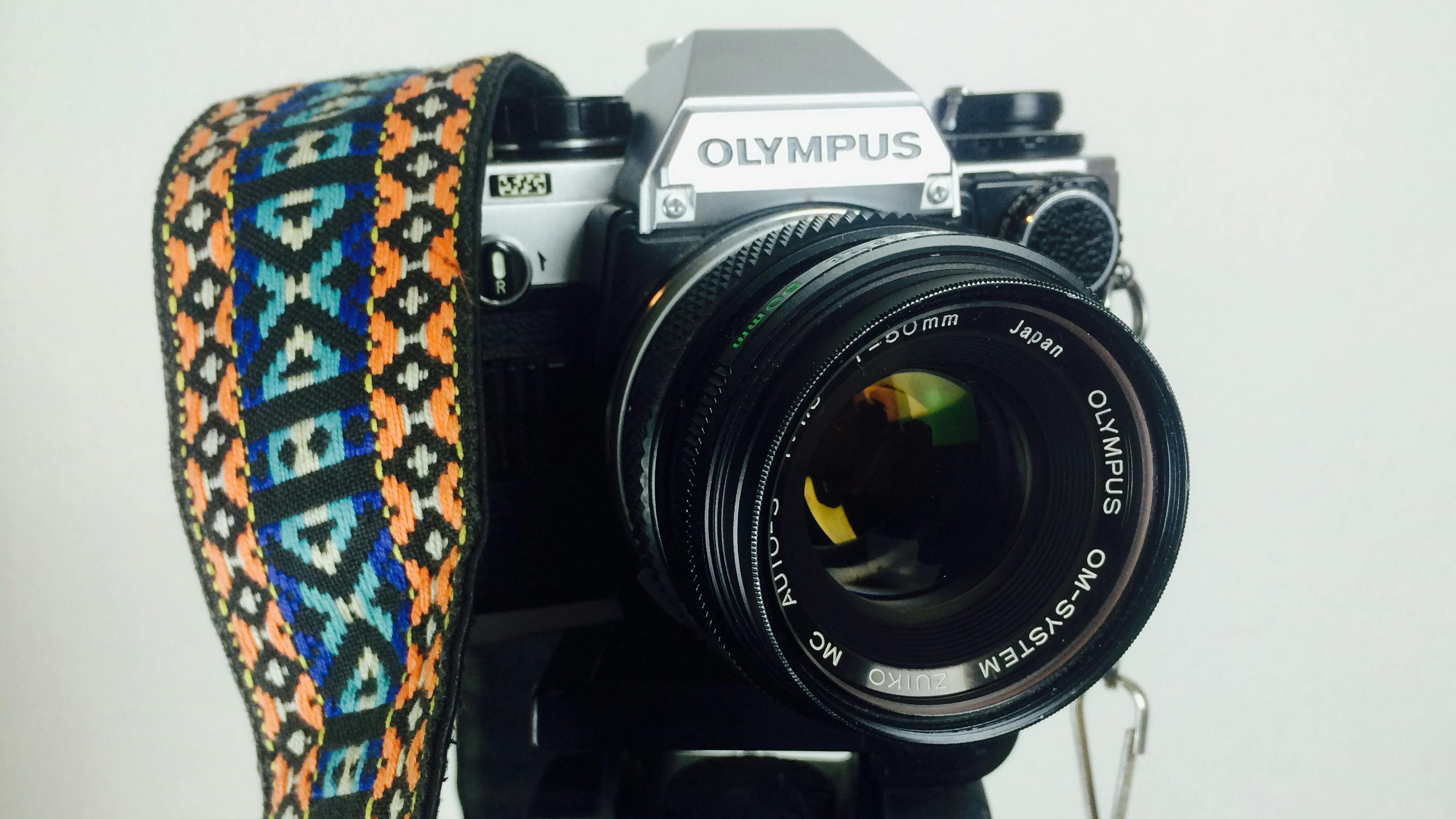 black and gray olympus dslr camera white orange blue and white strap