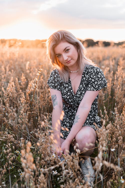 Free Photo of a Woman in a Floral Dress Crouching Near Grass Stock Photo