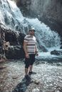 A Man Standing Near Strong Current of Waterfalls