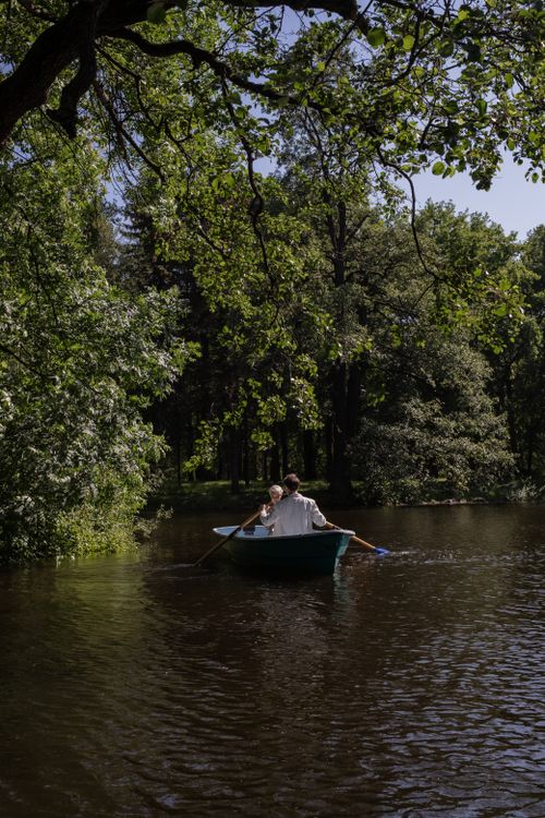 Free A couple enjoys a romantic row on a serene, tree-lined lake surrounded by nature. Stock Photo