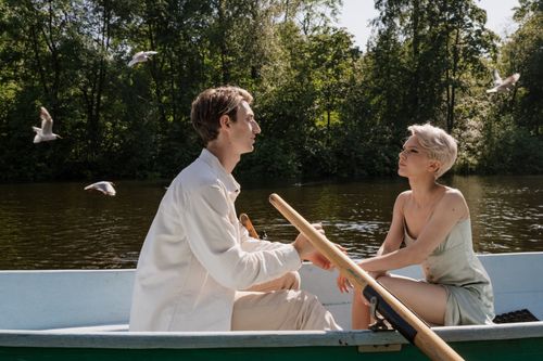 Free A romantic couple enjoying a boat ride on a peaceful lake surrounded by nature. Stock Photo