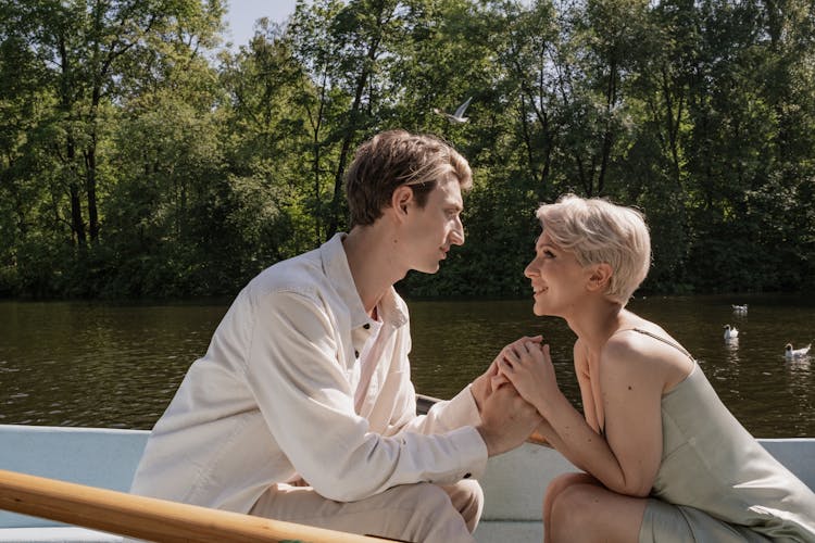 A Couple Sitting On The Boat While Holding Hands