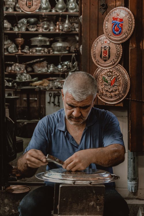 Man in Blue Polo Shirt Doing Metal Crafting