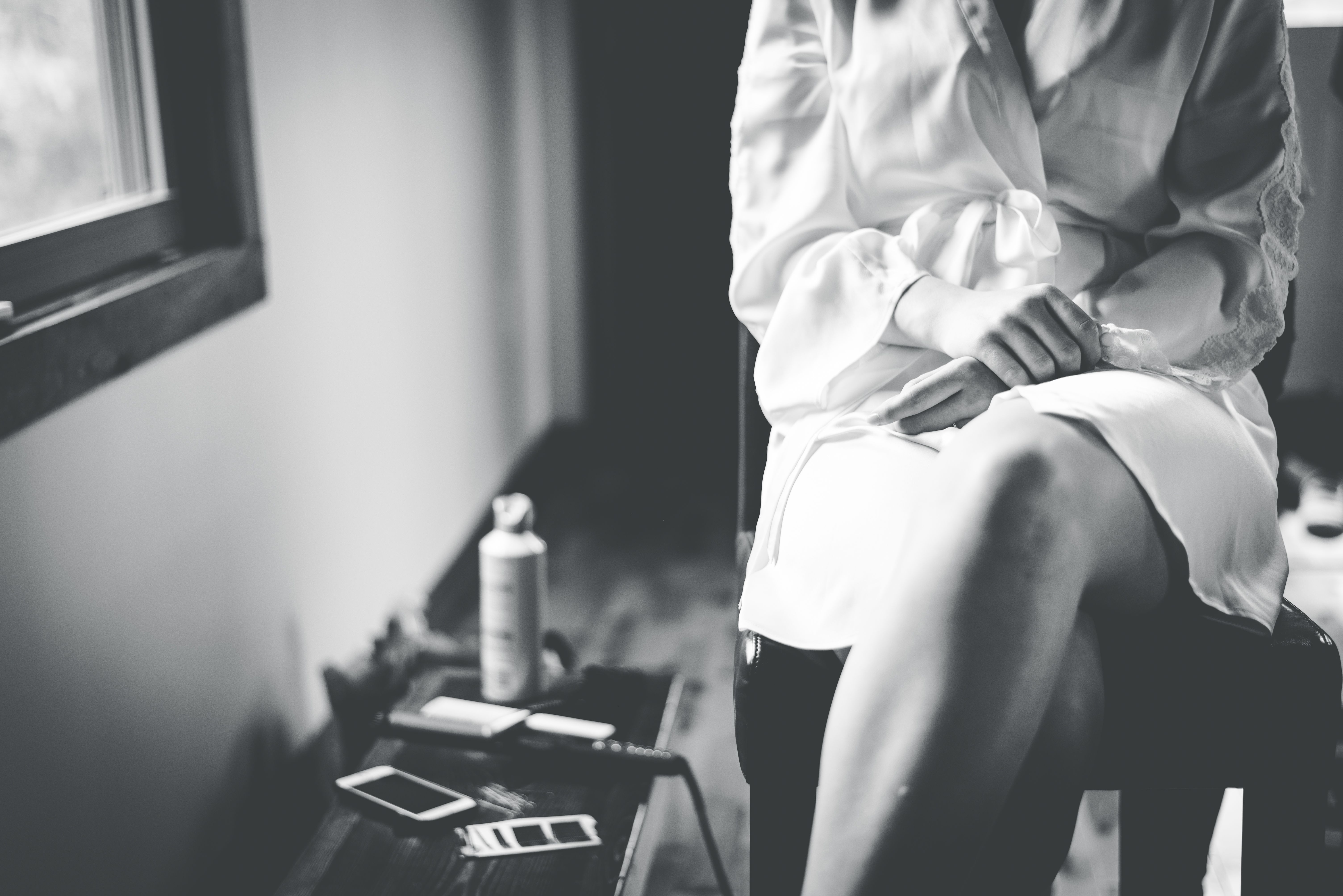 Black and white photo of a person in a robe, seated by a window, evoking calm.