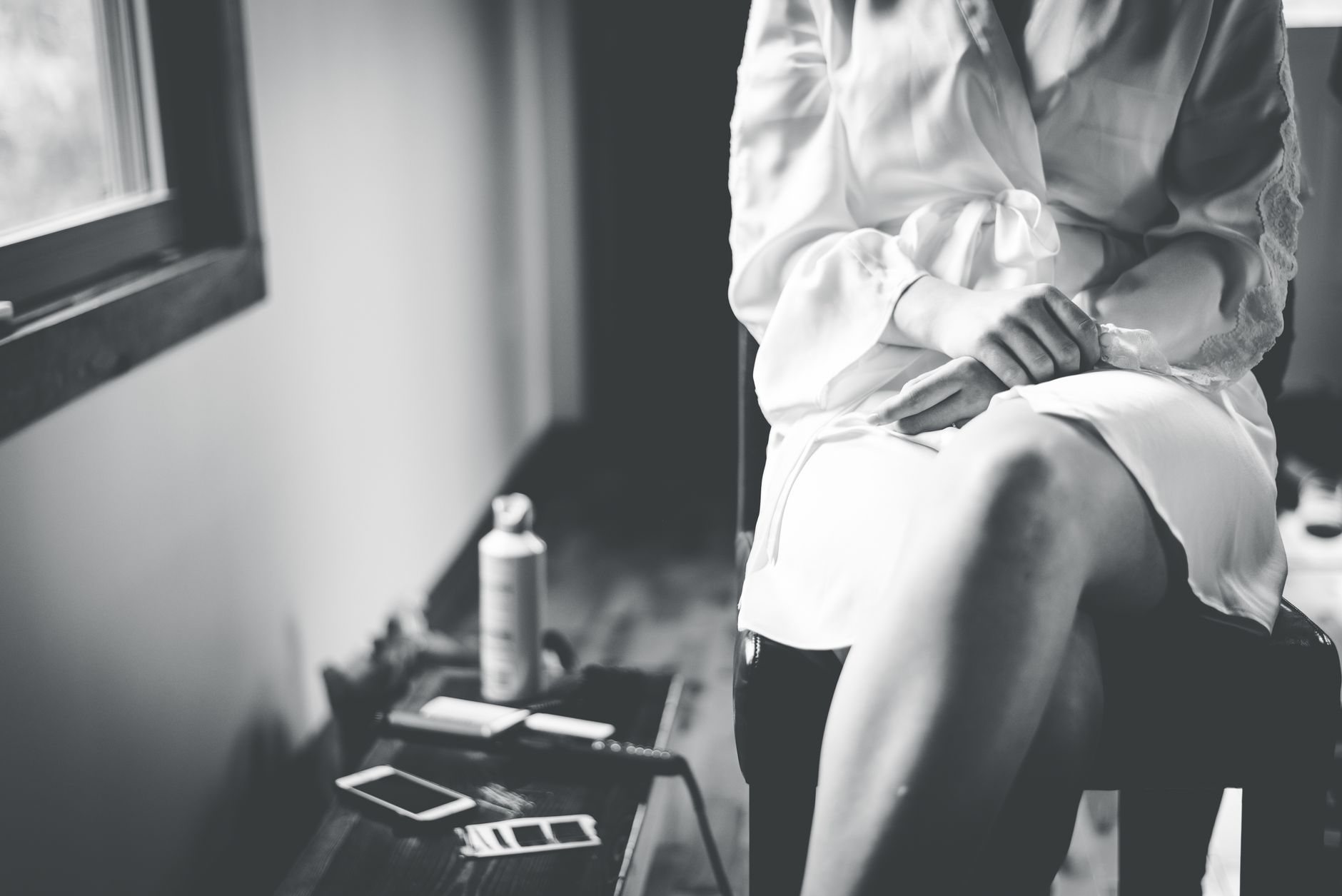 Black and white photo of a person in a robe, seated by a window, evoking calm.