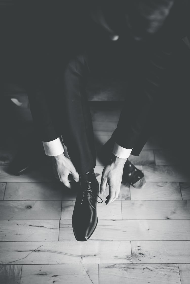 Man Putting On A Black Leather Shoe