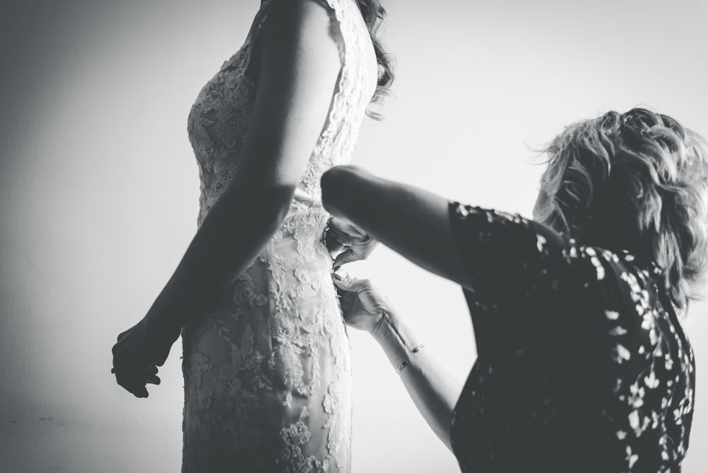 Tailor fitting a lace wedding gown at a final appointment
