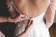 Close-up of hands adjusting a bride's dress, showcasing delicate details and elegance.