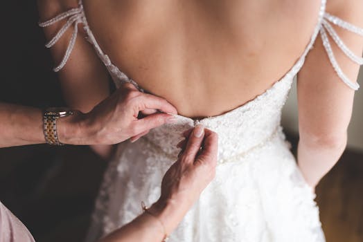 Close-up of hands adjusting a bride's dress, showcasing delicate details and elegance.