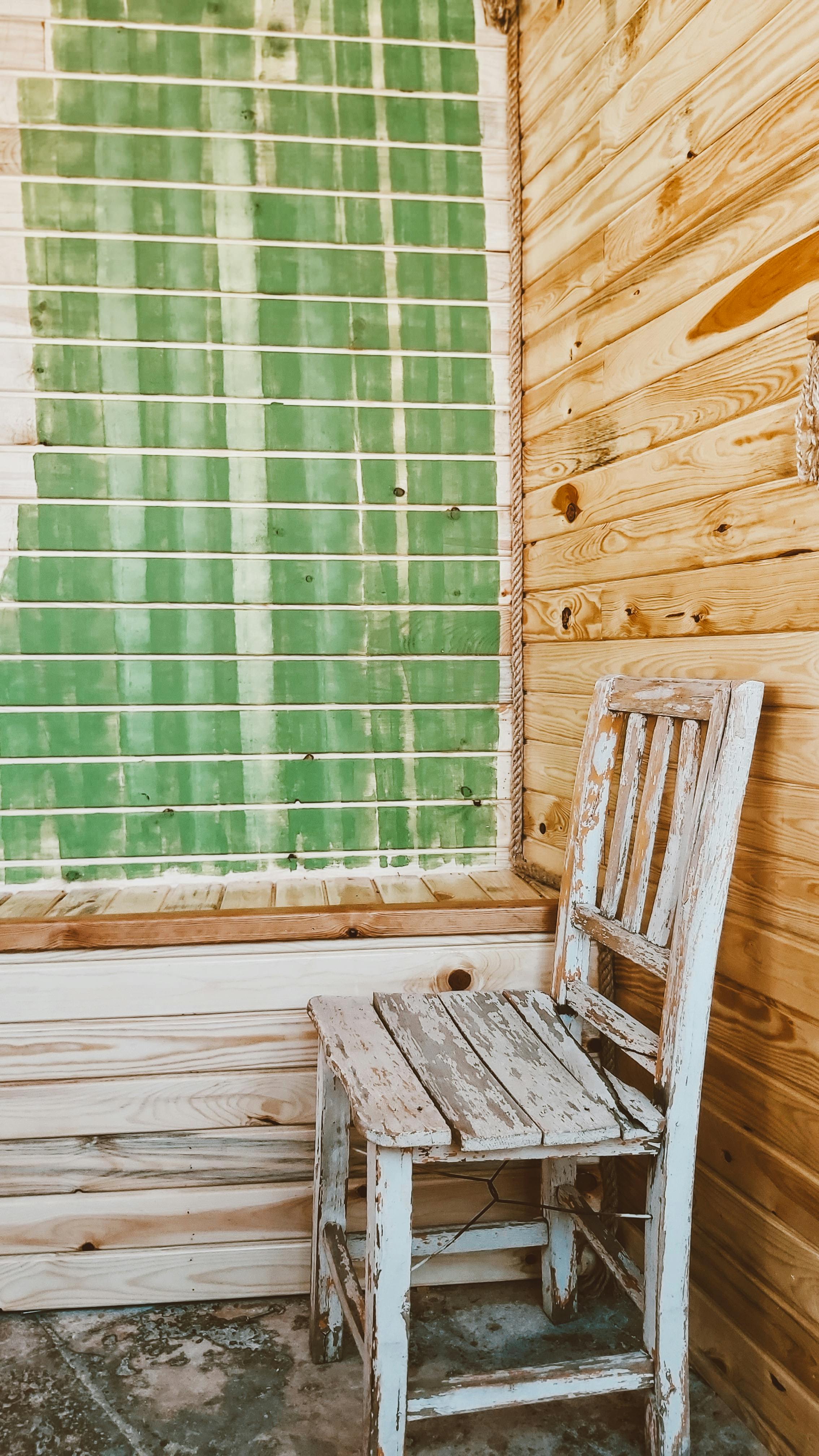 Free Vintage wooden chair beside a rustic window in a cozy wooden room. Stock Photo