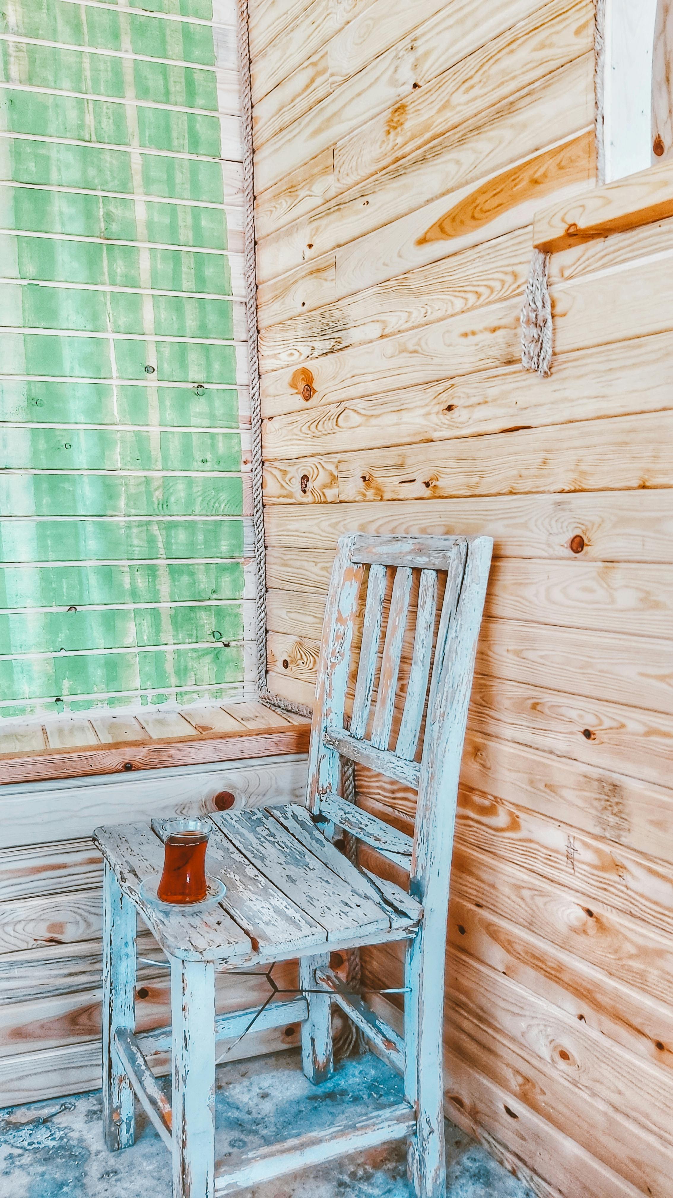 Free Wooden chair and glass of tea on a rustic porch, creating a cozy interior feel. Stock Photo